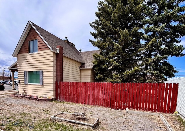 view of home's exterior featuring fence and roof with shingles
