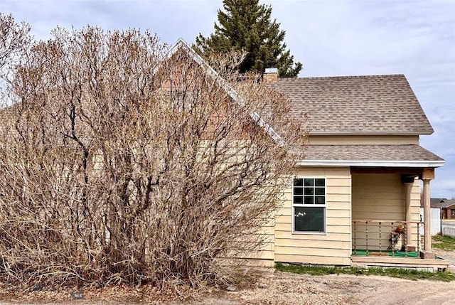 view of side of home with roof with shingles and a chimney