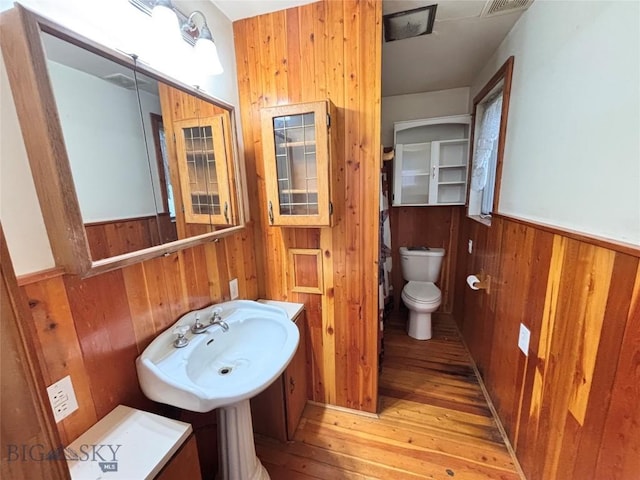 113 N Pacific St, Dillon, MT 59725 - bathroom with wood-type flooring, wooden walls, toilet, wainscoting, and a sink