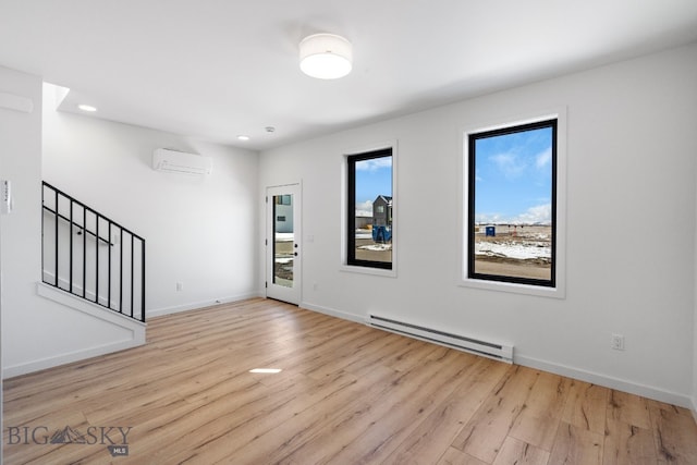 unfurnished living room with a wall mounted air conditioner, wood finished floors, a baseboard heating unit, baseboards, and stairs