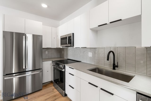 kitchen with appliances with stainless steel finishes, white cabinetry, and a sink