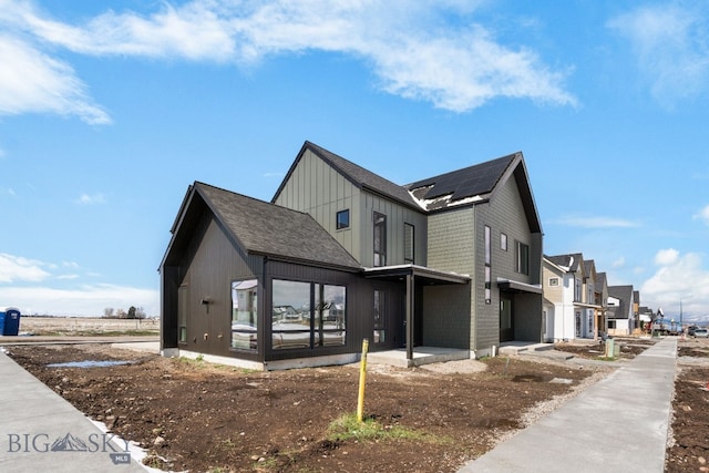 view of side of property with roof mounted solar panels, a shingled roof, and a residential view