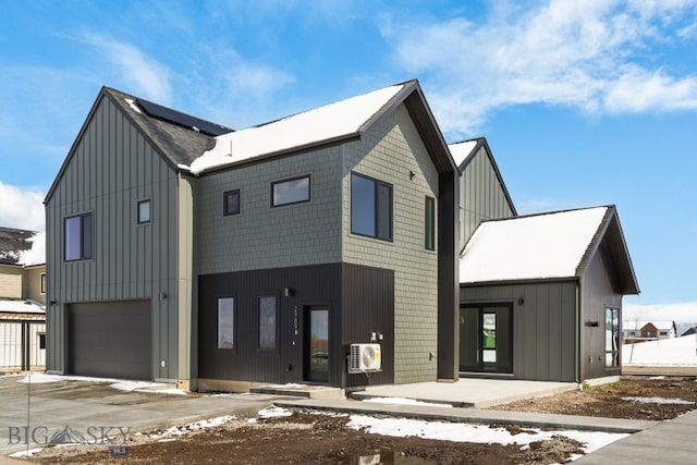 view of front of property with board and batten siding, roof mounted solar panels, an attached garage, and driveway