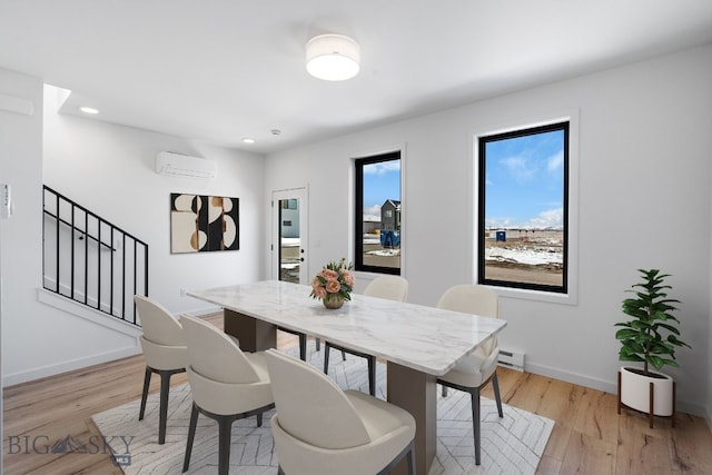 dining area with a wall unit AC, light wood-type flooring, baseboards, baseboard heating, and stairs