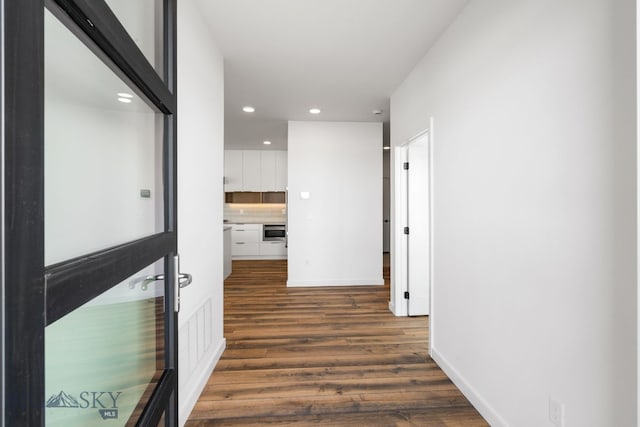 corridor with baseboards, recessed lighting, and dark wood-type flooring