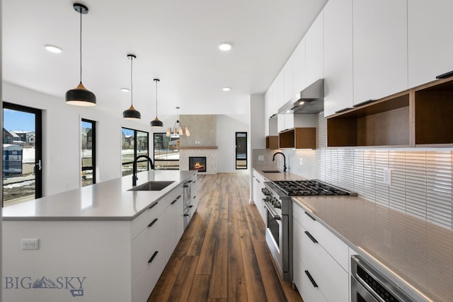kitchen featuring wall chimney exhaust hood, a sink, white cabinetry, high end range, and dark wood-type flooring