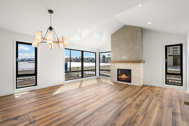 unfurnished living room featuring recessed lighting, a notable chandelier, lofted ceiling, wood finished floors, and a fireplace