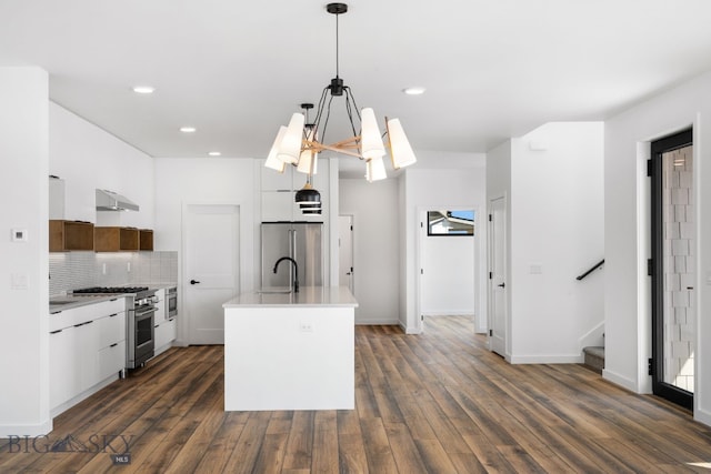 kitchen featuring stainless steel appliances, dark wood finished floors, tasteful backsplash, light countertops, and under cabinet range hood
