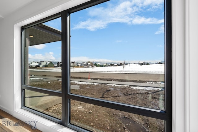 doorway to outside featuring a residential view, baseboards, and wood finished floors