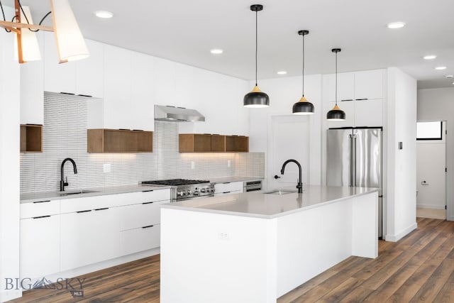 kitchen with a sink, tasteful backsplash, modern cabinets, light countertops, and under cabinet range hood