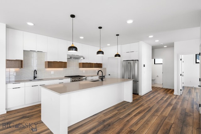 kitchen with stove, under cabinet range hood, a sink, and high end fridge