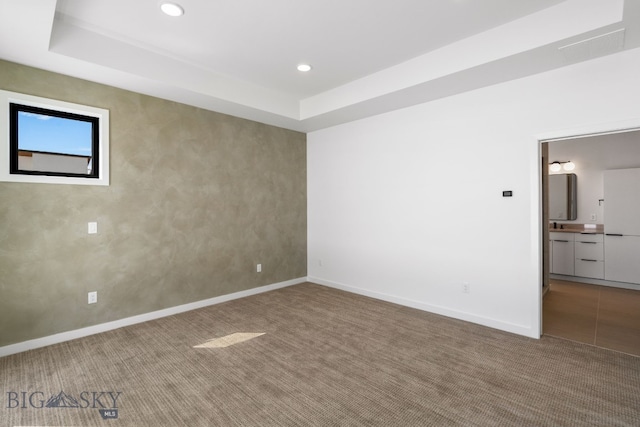 spare room with recessed lighting, carpet floors, a raised ceiling, and baseboards