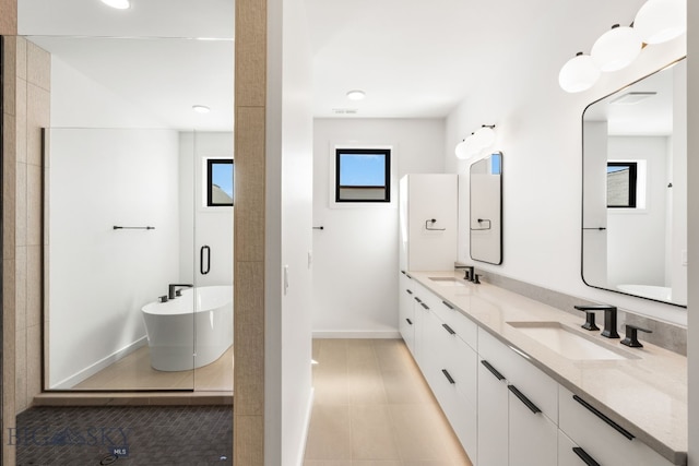 bathroom featuring baseboards, a soaking tub, a sink, and double vanity