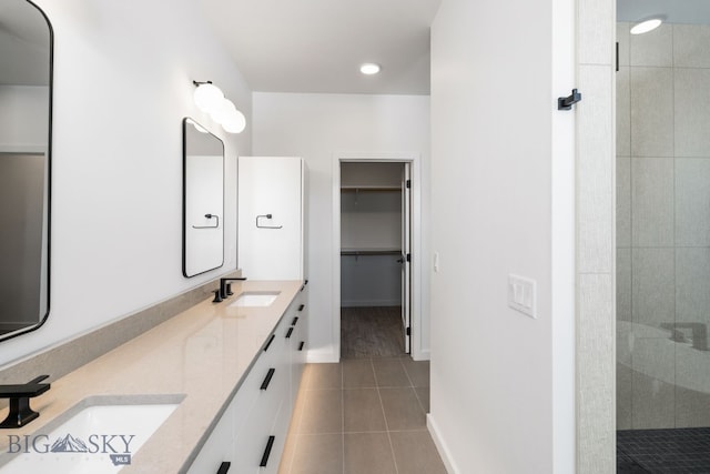 full bath with a spacious closet, tile patterned flooring, a stall shower, and a sink