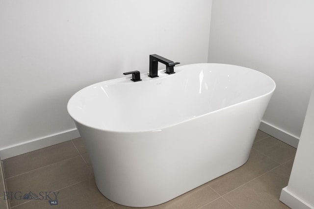 full bathroom with a soaking tub, baseboards, and tile patterned flooring