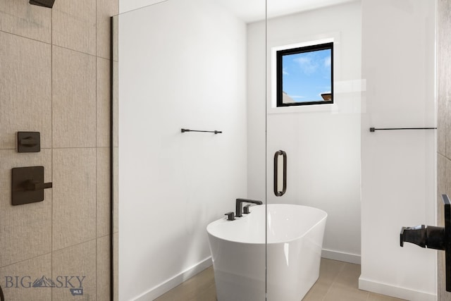 full bathroom with a soaking tub, tile patterned flooring, baseboards, and tiled shower
