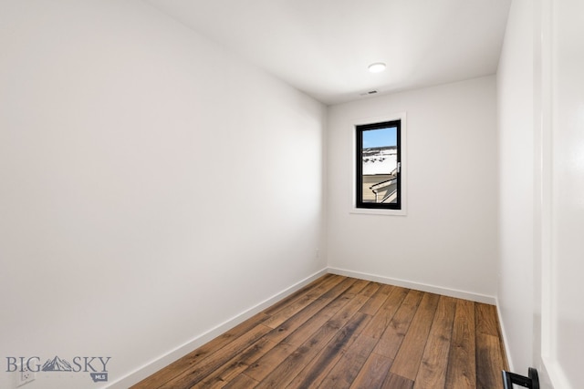 empty room featuring baseboards and dark wood-style floors