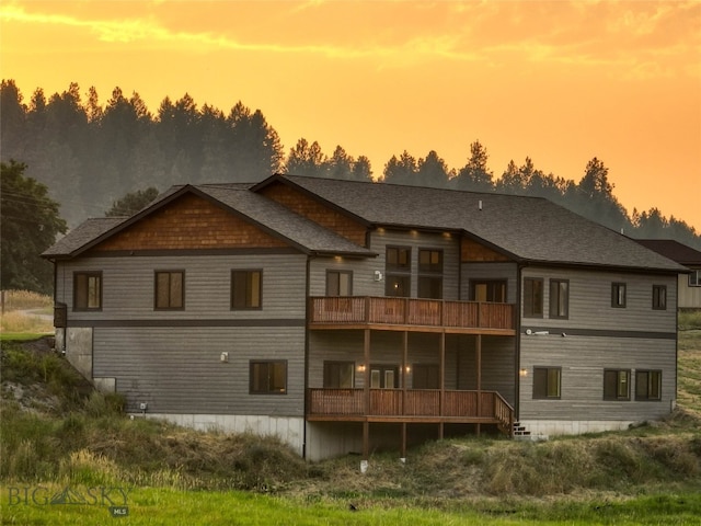 rear view of house with a shingled roof and a balcony