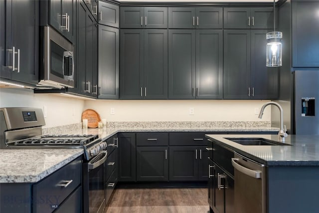 kitchen featuring a sink, stainless steel appliances, decorative light fixtures, dark wood finished floors, and light stone countertops