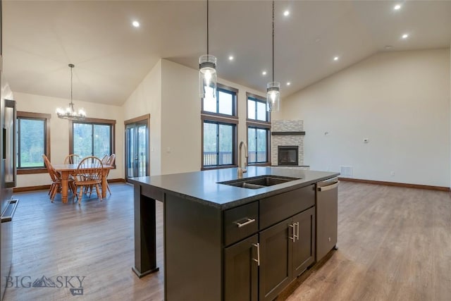kitchen with dishwasher, a sink, light wood-style flooring, and high vaulted ceiling