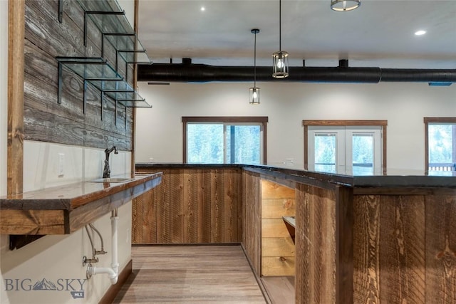 interior space with light wood finished floors, french doors, decorative light fixtures, and a sink