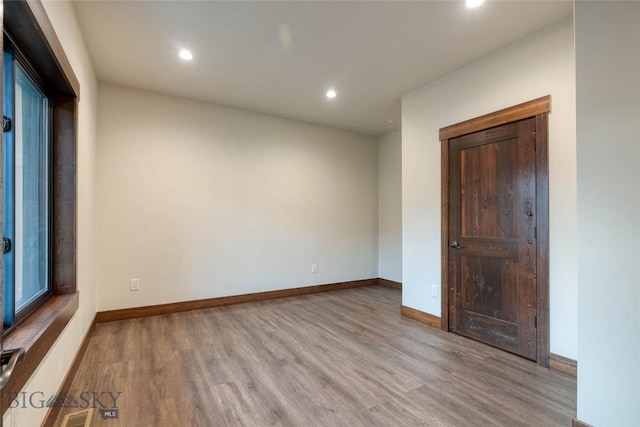 spare room with recessed lighting, wood finished floors, visible vents, and baseboards