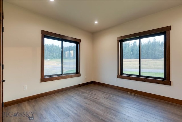 spare room featuring baseboards, visible vents, recessed lighting, and dark wood-style flooring