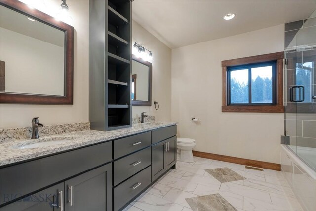 bathroom with baseboards, a sink, double vanity, and toilet