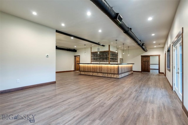 unfurnished living room featuring bar area, baseboards, wood finished floors, and recessed lighting