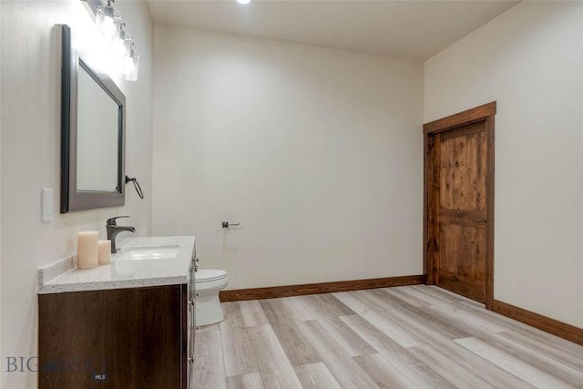 bathroom featuring baseboards, toilet, vanity, and wood finished floors