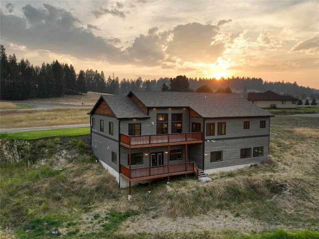 back of house at dusk with a balcony and a deck