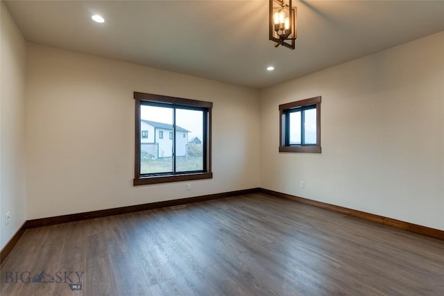 spare room with an inviting chandelier, baseboards, recessed lighting, and dark wood-type flooring