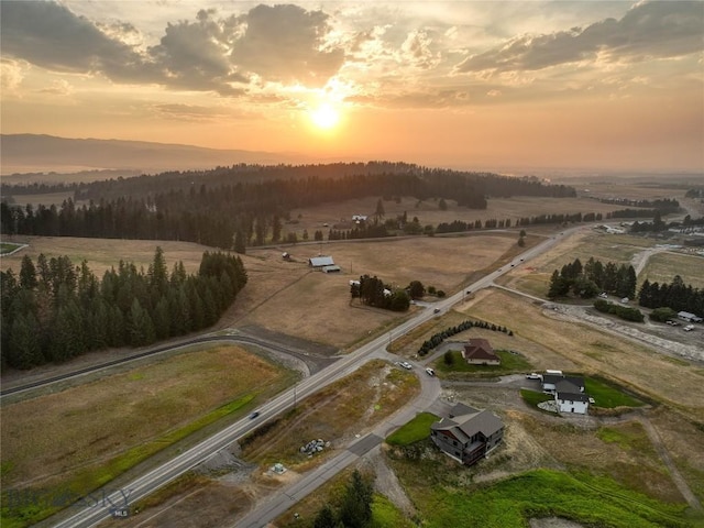 aerial view at dusk with a wooded view and a rural view