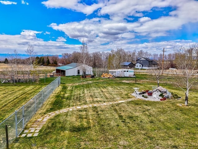 view of yard featuring fence, an outbuilding, a rural view, and a pole building
