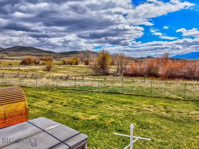 view of yard featuring fence, a rural view, and a mountain view