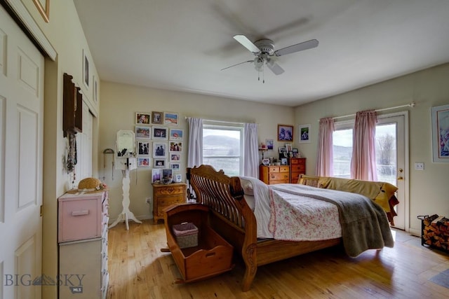 bedroom featuring light wood-type flooring, a ceiling fan, and multiple windows