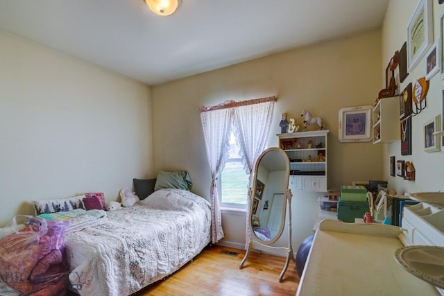 bedroom featuring wood finished floors, visible vents, and baseboards
