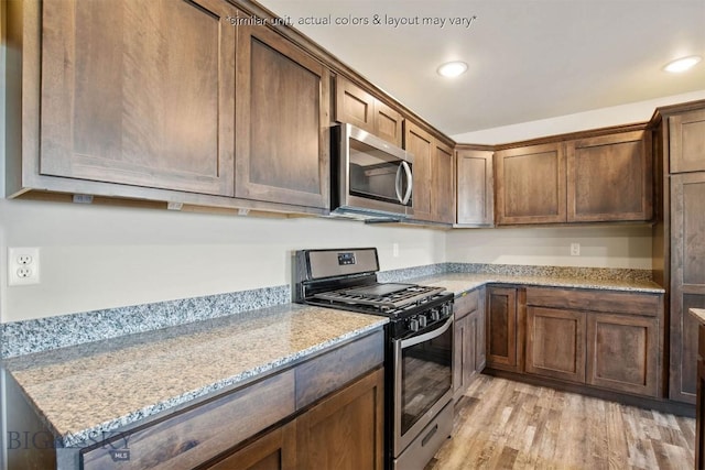 kitchen with recessed lighting, light wood-style floors, light stone countertops, and appliances with stainless steel finishes