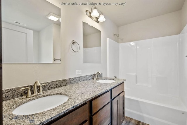 bathroom featuring double vanity, bathing tub / shower combination, wood finished floors, and a sink