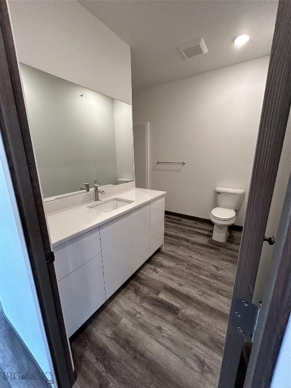 bathroom featuring wood finished floors, visible vents, toilet, and vanity