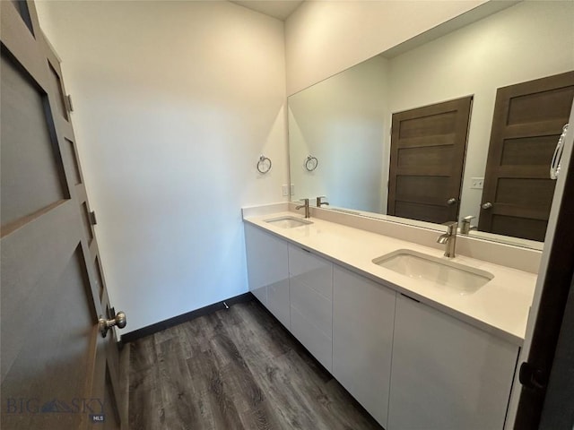 full bathroom featuring baseboards, wood finished floors, a sink, and double vanity