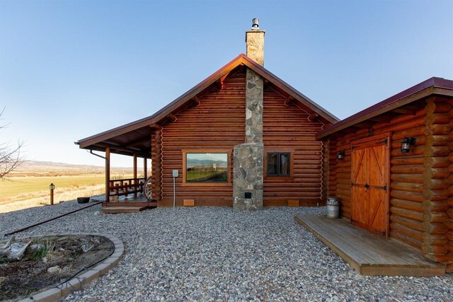rear view of house with crawl space, a chimney, and log exterior