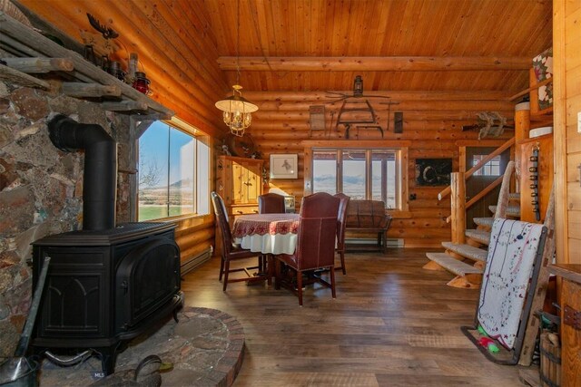 dining area featuring wooden ceiling, wood finished floors, rustic walls, and a wood stove