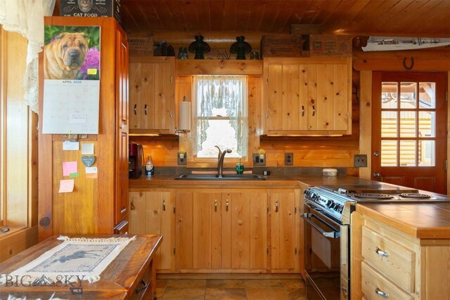 kitchen featuring a peninsula, a sink, wood ceiling, tile counters, and stainless steel range