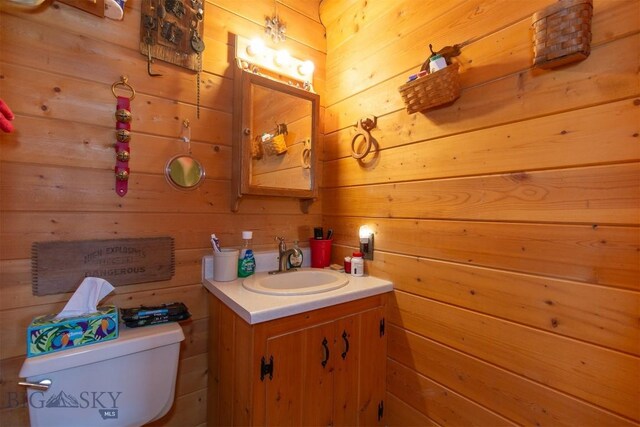 bathroom with wood walls, toilet, and vanity