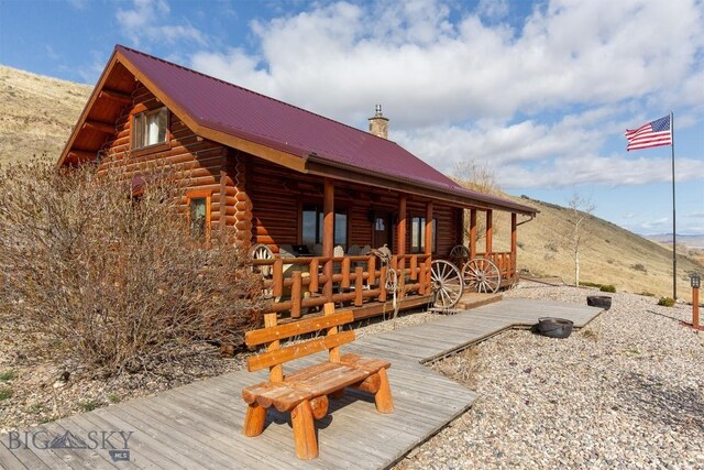 view of side of home featuring a chimney, log exterior, a mountain view, and metal roof