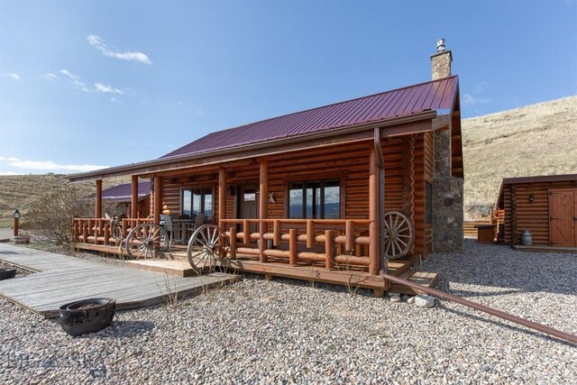 view of front of property featuring a chimney, metal roof, and log siding