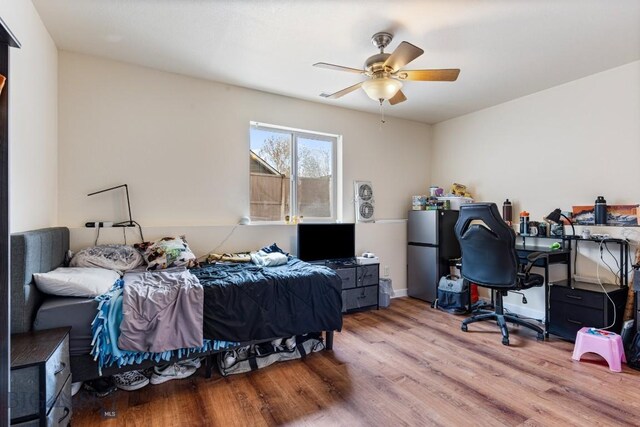 250 Jackson Ln, Belgrade, MT 59714 - bedroom featuring freestanding refrigerator, wood finished floors, a desk, and ceiling fan