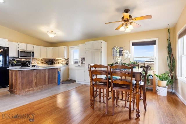 dining area featuring a ceiling fan, vaulted ceiling, light wood finished floors, and a wealth of natural light