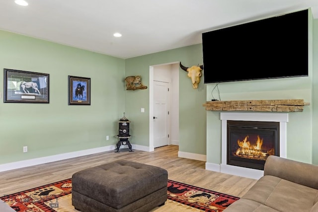 living room featuring light wood-style floors, baseboards, a glass covered fireplace, and recessed lighting